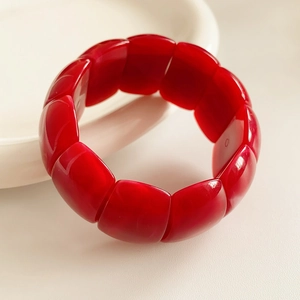 Macro shot of deep red acrylic geometric beads on an elastic bracelet with a glossy finish