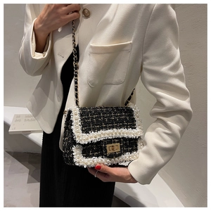 Detail of black tweed shoulder bag featuring pearl trim and golden chain strap