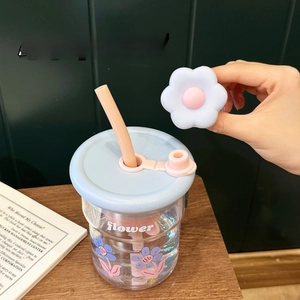 Détail du couvercle de paille en silicone fleur bleue avec anneau anti-perte sur verre