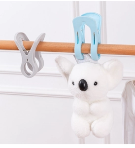 Detail of blue and grey windproof clips holding a koala toy on a wooden rod