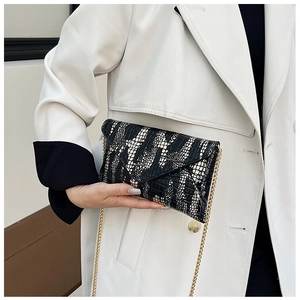 Close-up of black and white crocodile texture envelope bag with gold chain strap