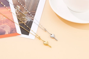 Detailed view of polished gold and silver heart key pendants on stainless steel necklaces