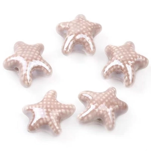 Close-up of five glazed ceramic starfish beads in light pink with white polka dots