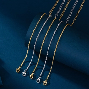 Close-up of satellite chains with beads and lobster clasp in gold and silver finishes