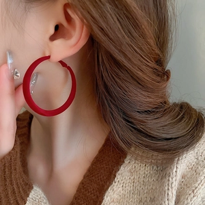 Close-up of a model wearing large red flocked geometric hoop earrings in a matte finish
