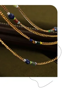 Close-up of vintage gold necklace with lapis, turquoise, and tiger eye beads on velvet