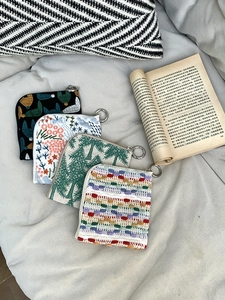 Flat lay of four different embroidered linen mini pouches in diverse patterns and colors