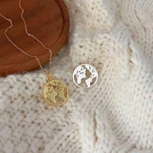 Detail of gold and silver world map round pendants on soft knit sweater background