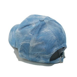 Detailed close-up of blue denim baseball cap with marble wash pattern and metal buckle