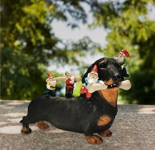 Detail of dachshund garden statue with colorful gnomes and bone on stone surface