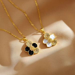 Detail of floral pendant necklaces in gold with black and white enamel and crystals
