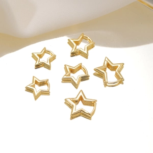 Close-up of six gold star-shaped copper hoop earrings on a reflective studio surface