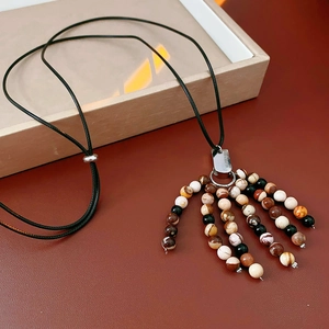 Detail of vintage beaded pendant necklace with earthy stones on black braided cord