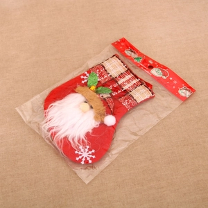 Detail of red Santa Claus stocking with plaid ankle cuff and bell in retail packaging