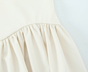 Détail macro du plissage fin et texture du tissu d'une robe licou rayée de couleur crème