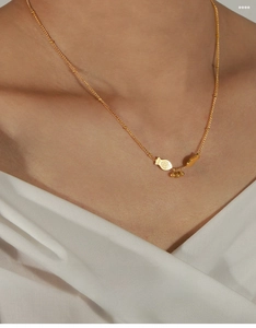 Macro detail of golden fish pendant with three hanging beads on a fine titanium chain