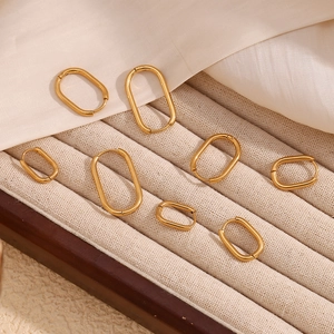 Minimalist gold U-shaped hoop earrings in various sizes on beige velvet tray