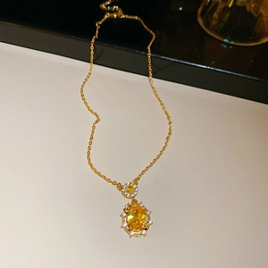 Macro view of 18k gold plated necklace with oval yellow gemstone and white zircon accents