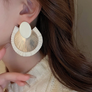 Detail of bohemian raffia fan earrings with gold-toned texture on a model