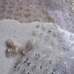 Detail of gold and silver butterfly and flower nail stickers with metallic reflective finish