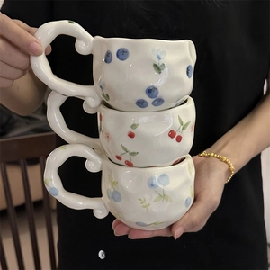 Three stacked ceramic mugs with irregular hand-painted fruit patterns and creative handles
