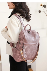 Detail of dusty pink backpack featuring tassel charm and geometric webbing strap