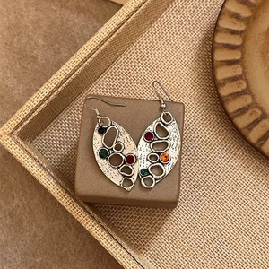 Vue détaillée de boucles d'oreilles feuille vintage avec strass colorés sur décor rustique