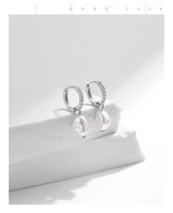 Macro detail of 925 silver earring with sparkling cubic zirconia and baroque pearl drop