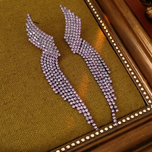 Macro shot of long purple rhinestone tassel earrings with a vintage geometric wing design