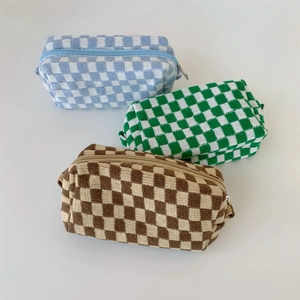 Three knitted checkered makeup bags in blue, green, and brown colors on white background