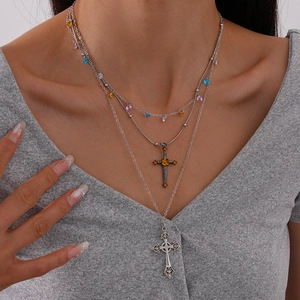 Close-up of layered vintage silver necklaces with cross pendants and amber stone detailing