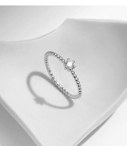 Macro shot of silver beaded ring featuring a round sparkling moissanite gemstone