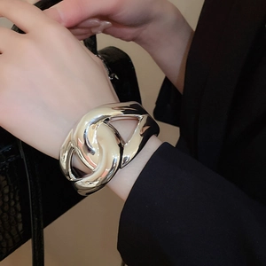 Detailed view of a wide twisted silver metal cuff bracelet styled on a model's wrist