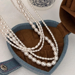 Detailed view of layered rice pearl necklace placed inside a denim heart jewelry box