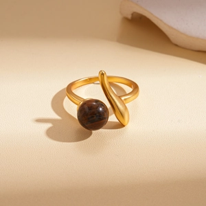 Detailed macro shot of a golden textured open ring featuring a brown tiger eye stone