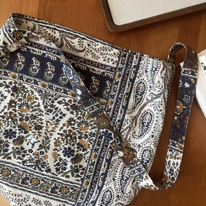 Detail of bohemian paisley cotton linen tote bag with wide shoulder strap on wooden desk