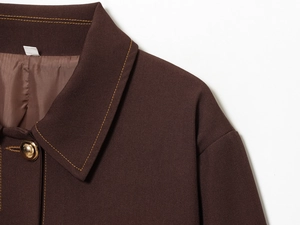 Detail of brown jacket showing gold buttons, twill texture, and yellow contrast stitching