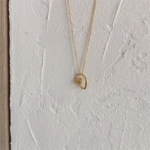 Detail of minimalist gold double interlocking ring pendant necklace on white background