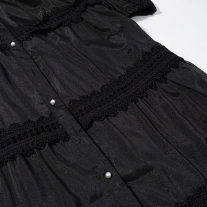 Macro shot of black dress fabric with lace trimming and white pearl buttons detail