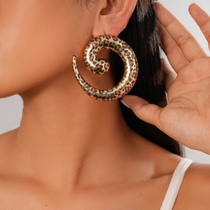 Close-up of leopard print spiral hoop earrings worn by a model in golden finish