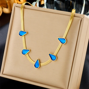 Gold snake chain necklace featuring five elegant blue teardrop gemstones on a beige box
