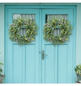 Artificial eucalyptus berry wreaths hanging on a blue door for festive wall decor