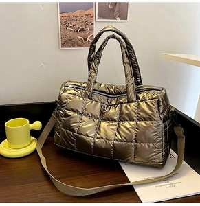 Detail view of a gold quilted tote bag with cross-stitch pattern on a wooden table
