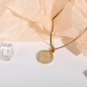 Macro shot of gold four-leaf clover pendant necklace on textured beige paper