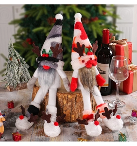 Close-up of plush Christmas gnomes with reindeer antlers and long legs on a wood stump