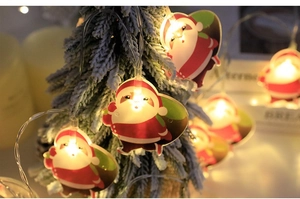 Close-up of LED Santa Claus string lights with warm glow on a snowy Christmas tree