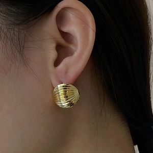 Detail of 18K gold earring with textured radial patterns on a spherical surface