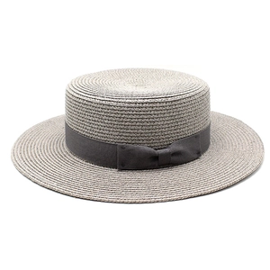 Detailed texture of flat-top boater straw hat featuring elegant side bow and grey ribbon