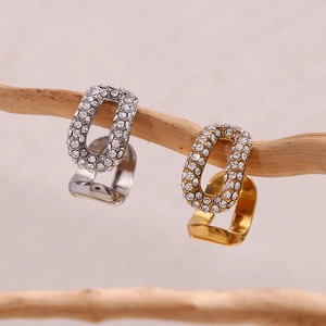 Vista macro di orecchini a clip a U in oro e argento con zirconi incastonati su un ramo