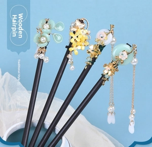Close-up of four vintage wooden hair sticks with floral accents and silk tassels